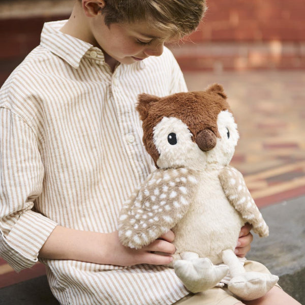Child holding a plush owl toy on a stone floor.
